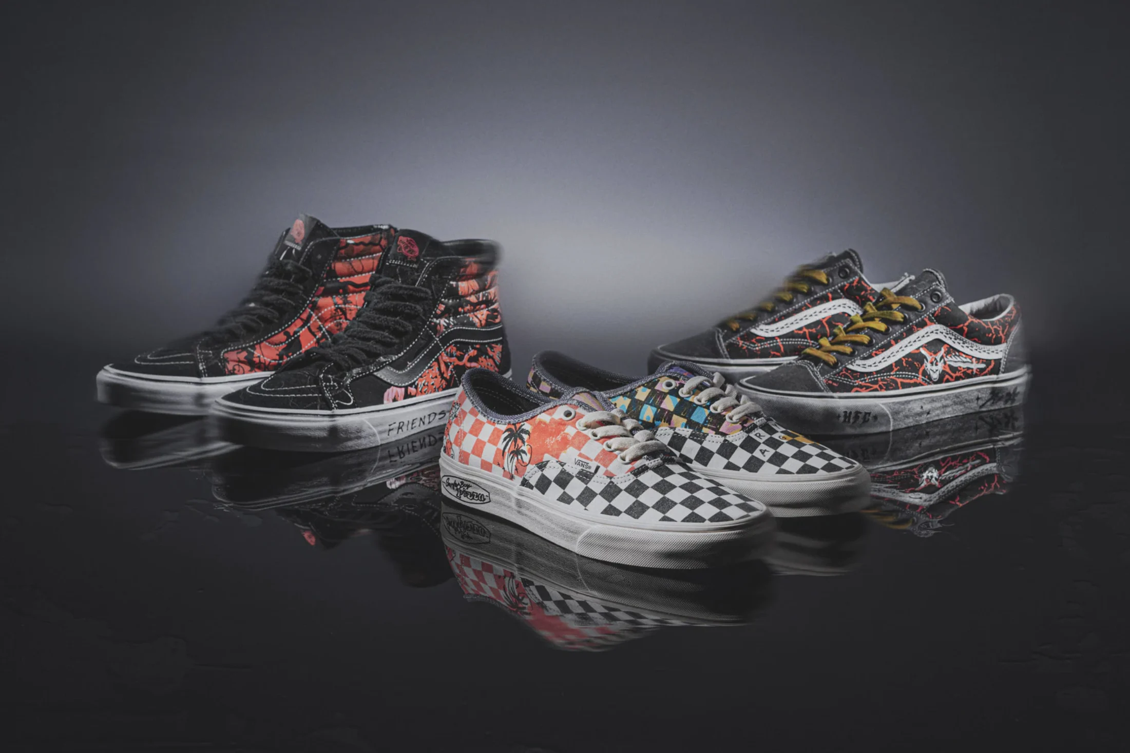 Three sneakers from the Stranger Things x Vans collection on a dark reflective surface: a black high-top and a low-top with red “Upside Down” vine graphics, and a checkerboard slip-on.